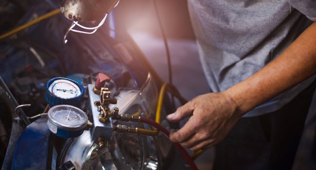 Mechanic repairing a car,Check car air conditioning system refrigerant recharge,Auto mechanic Worker hands holding and point to monitor to check and fixed car air conditioner system in car service.